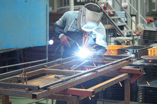 A man welding metal in an industrial setting.